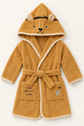 A plush hooded bathrobe for a child, styled like a lion cub, in a warm golden-brown terry cloth with cream trim. The hood features embroidered lion face details, and the front pockets are printed with 'MON PETIT LION'.